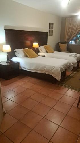 a bedroom with two beds and two lamps on tables at The Gateway Inn in Louis Trichardt