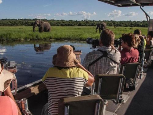 a group of people riding in a boat on a safari at Nxabii Cottages in Kasane