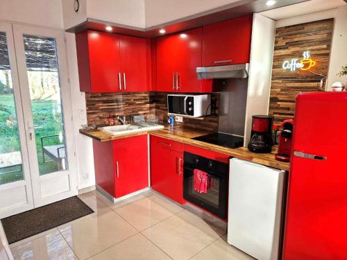 a kitchen with red cabinets and a red refrigerator at 02 - Très joli 2 pièces avec 3 lits pouvant accueillir jusqu'à 5 personnes, situé au rdc avec entrée indépendante, une place de parking réservée devant l'entrée et terrasse sur l'arrière donnant sur parc arboré, tout le linge de maison est fourni in Razac-sur-lʼIsle