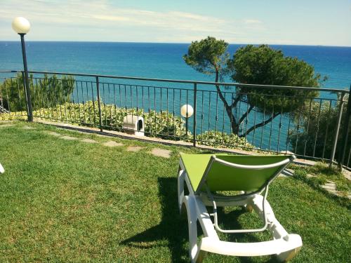 a green chair sitting on the grass near the ocean at Agriturismo La Collarina in Imperia