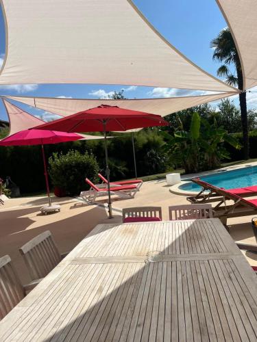 - une table avec un parasol rouge à côté de la piscine dans l'établissement Maison de vacances avec piscine à 5 minutes de Périgueux, à Trélissac