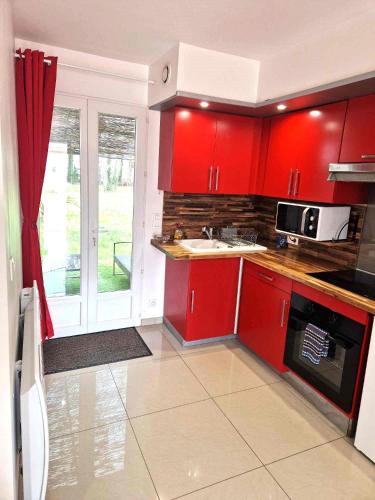 une cuisine avec des armoires rouges et un micro-ondes dans l'établissement 02 - Très joli 2 pièces avec 3 lits pouvant accueillir jusqu'à 5 personnes, situé au rdc avec entrée indépendante, une place de parking réservée devant l'entrée et terrasse sur l'arrière donnant sur parc arboré, tout le linge de maison est fourni, à Razac-sur-lʼIsle