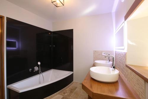 une salle de bain avec une baignoire blanche et un lavabo dans l'établissement Le Petit Val d'or - Piscine & Plein air, à Saint-Prix
