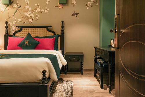 a bedroom with a bed with red pillows and a dresser at Hanoi Bliss Hotel in Hanoi