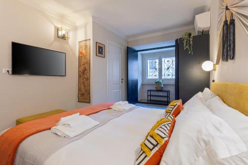 a bedroom with a bed with white sheets and a flat screen tv at Rome As You Feel - Charming Space at Torre Argentina in Rome