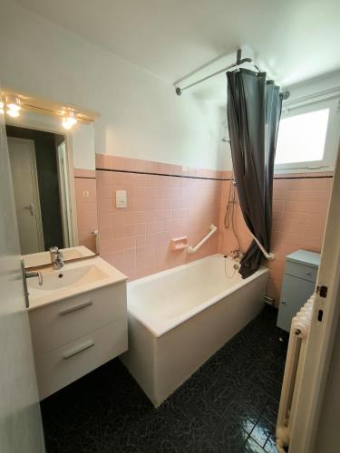 La salle de bains est pourvue d'une baignoire, d'un lavabo et d'un parasol. dans l'établissement Appartement 4 pers, 2 chambres, en RDC d'une maison, à Luz Saint Sauveur, Hautes-Pyrénées, à Luz-Saint-Sauveur