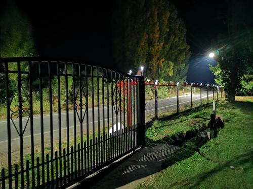 a wrought iron fence next to a road at night at Molina, cerca de 7 Tazas, campo con animales in Curicó