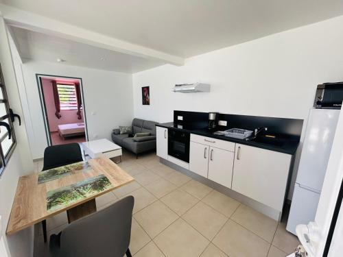 Appartement SOLEIL في كايان: مطبخ وغرفة معيشة مع طاولة وأريكة