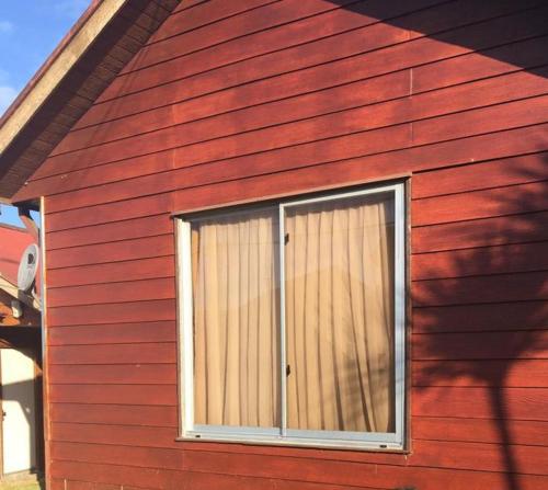 a window on the side of a red house at Casa castro chiloe in Castro