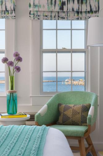 a bedroom with a green chair and a window at Summercamp in Oak Bluffs