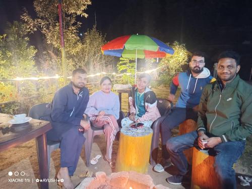 a group of people sitting around a table with an umbrella at Moonlight Camp Dhanachuli Mukteshwar in Nainital