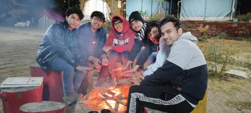 a group of people sitting around a fire at Moonlight Camp Dhanachuli Mukteshwar in Nainital