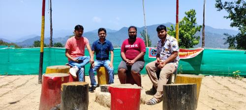a group of men sitting on tree stumps at Moonlight Camp Dhanachuli Mukteshwar in Nainital