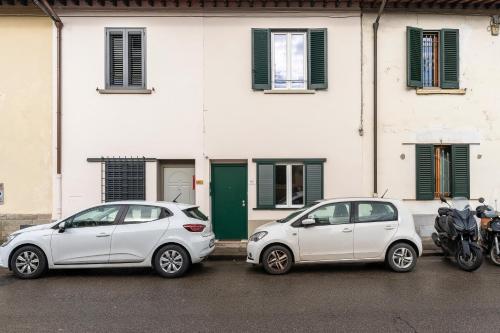 two white cars parked in front of a building at Scandicci Elite Home - Casa Moderna con Cortile e Parcheggio Gratuito in Scandicci