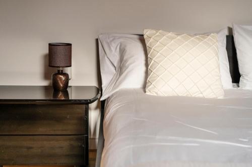 a white bed with a pillow and a night stand at Scandicci Elite Home - Casa Moderna con Cortile e Parcheggio Gratuito in Scandicci