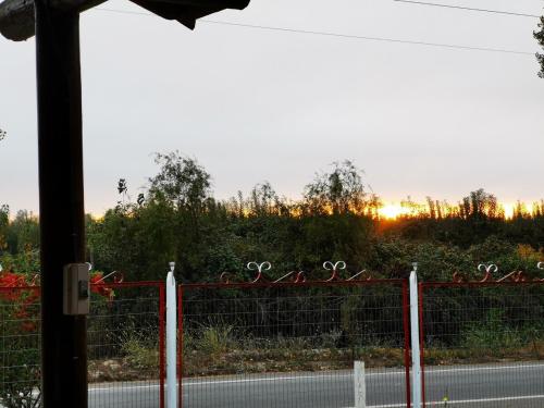 a fence on a road with the sunset in the background at Molina, cerca de 7 Tazas, campo con animales in Curicó