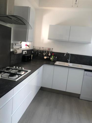 une cuisine avec des armoires blanches et un four à plaques de cuisson dans l'établissement les peupliers, à Royan