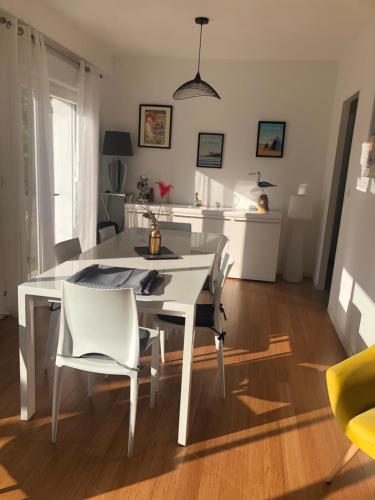 - une table à manger blanche et des chaises dans la cuisine dans l'établissement les peupliers, à Royan