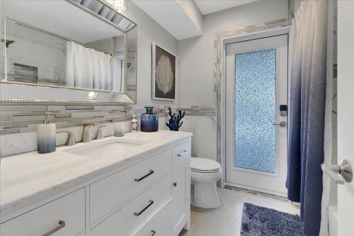 a bathroom with a sink and a toilet and a mirror at Neptunes Villa-Canalfront, Heated Pool, Outdoor Kitchen, Tiki Hut in Cape Coral