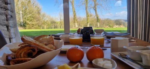 una mesa con un plato de pan y vasos de zumo de naranja en Hotel et restaurant Le Clos De La Prairie, en Gouy-Saint-André