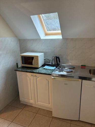 a small kitchen with a microwave and a stove at Lóbarát Panzió in Cserszegtomaj