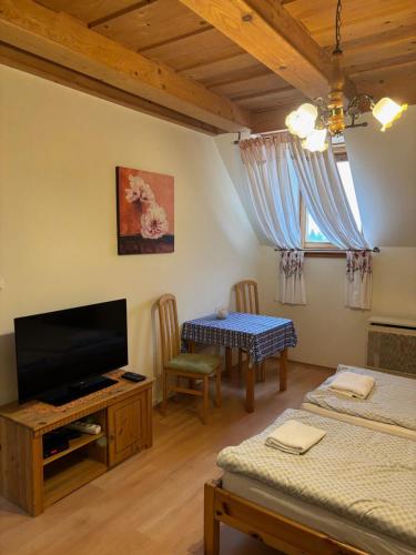a living room with a flat screen tv and a table at Lóbarát Panzió in Cserszegtomaj