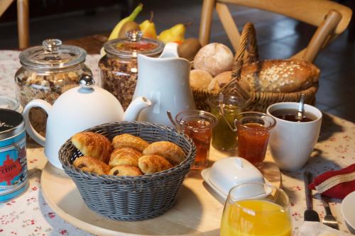 une table avec un panier de pâtisseries sur une table dans l'établissement Le Manoir du Pont Senot, à Noron-la-Poterie