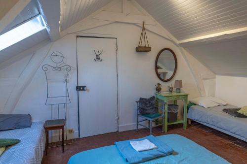 a room with two beds and a door with a dress on the wall at Chambre d'Hôtes Les Jardins de Marie, SCI Charles III in Bernay