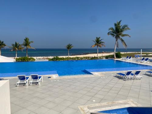 a swimming pool with chairs and the beach at Sifah seaCottage in Muscat