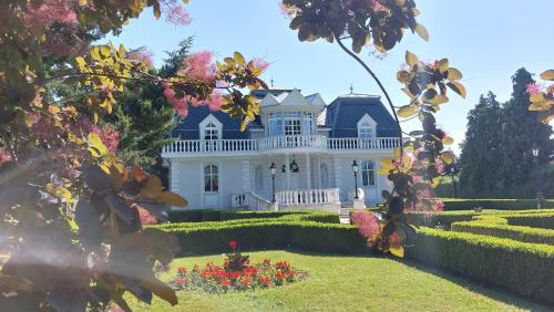 a large white house with a garden and flowers at Castle Garden in Szombathely