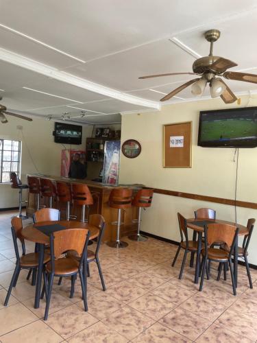 a bar with tables and chairs in a room at Wellcome Dover Lodge in Lusaka