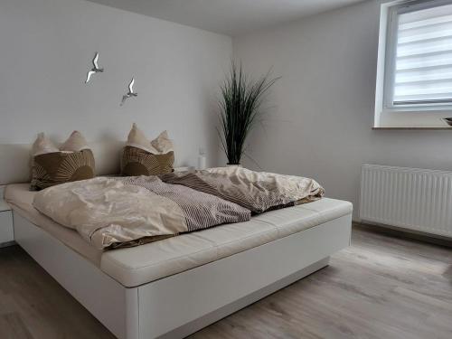 ein weißes Bett in einem weißen Zimmer mit einer Pflanze in der Unterkunft Lounge 1 in Koblenz