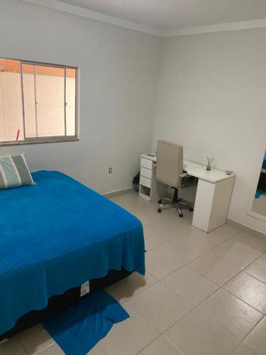 a bedroom with a blue bed and a desk at Casa aconchegante in Porto Seguro