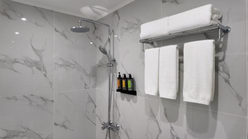 a bathroom with a shower with towels and bottles of wine at CC LUX Suites in Piraeus