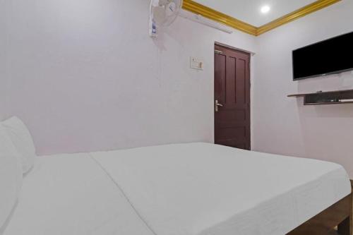 a white bedroom with a bed and a television at v guest inn in Hyderabad