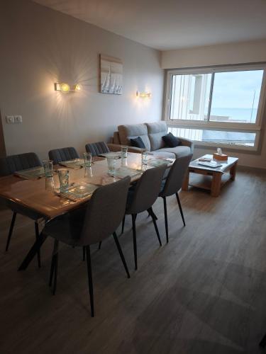 a living room with a table and chairs and a couch at Appartement rénové avec vue sur mer à Fécamp ! in Fécamp