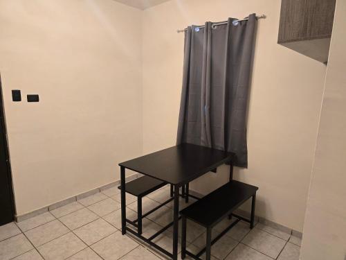 a black table and chair in a room with a curtain at De la llanura 31 in Hermosillo