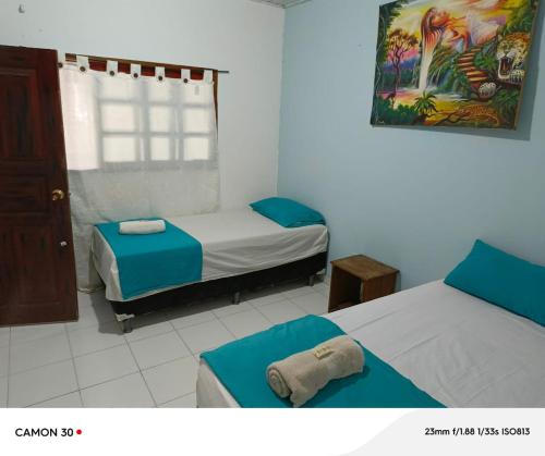 a bedroom with two beds and a painting on the wall at Alojamiento LETICIA in Leticia