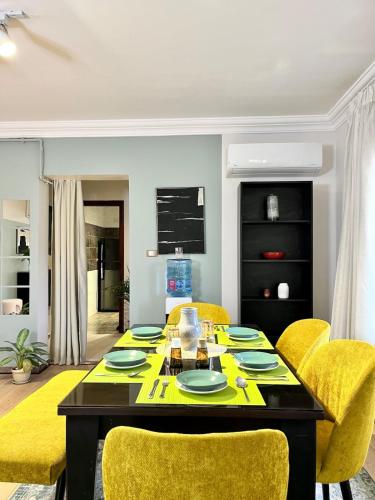 a dining room with a table and yellow chairs at 6th of October Sun & Shade in 6th Of October