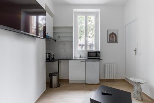 une cuisine blanche avec un évier et un micro-ondes dans l'établissement Montbrun Alésia II Cosy studio 2P, à Paris
