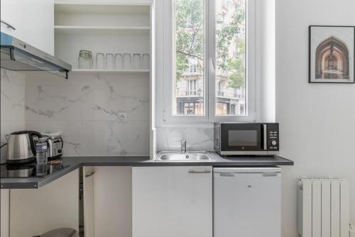 une cuisine avec un évier et un micro-ondes dans l'établissement Montbrun Alésia II Cosy studio 2P, à Paris
