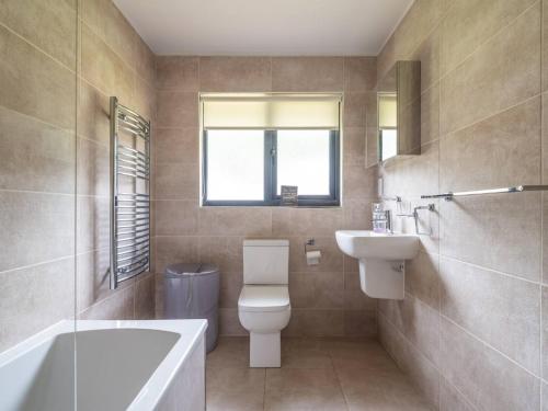 a bathroom with a toilet and a sink and a tub at Cabin W Hot Tub, Outdoor Dining In National Park in Otterburn