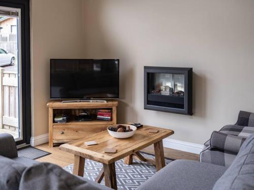 a living room with a tv and a coffee table at Lodge W Hot Tub, Outdoor Dining In National Park in Otterburn