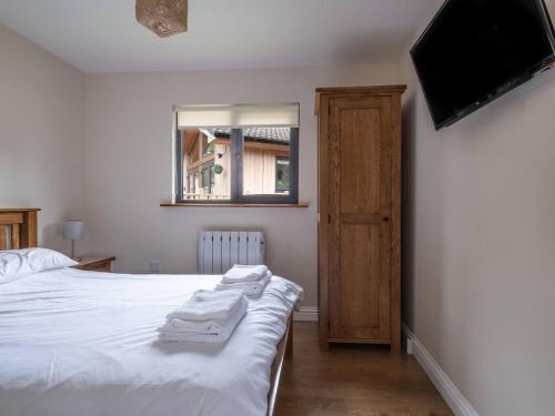 a bedroom with a bed with white sheets and a flat screen tv at Lodge W Hot Tub, Outdoor Dining In National Park in Otterburn