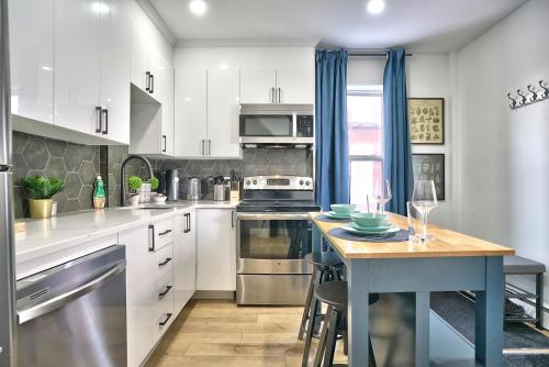 a kitchen with white cabinets and a blue island with a table at Sherby LUX - Central, Parking, Renovated, Sleeps 6 in Sherbrooke