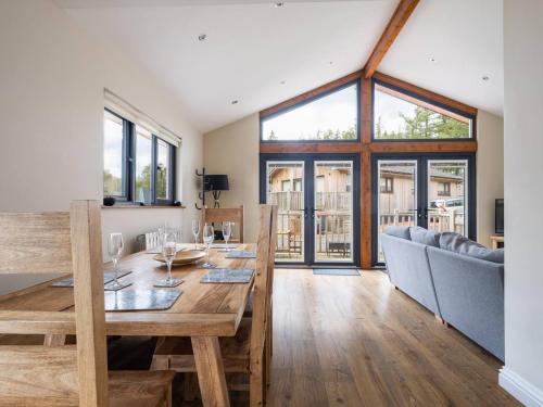 a dining room with a wooden table and a large window at Lodge W Hot Tub, Outdoor Dining In National Park in Otterburn