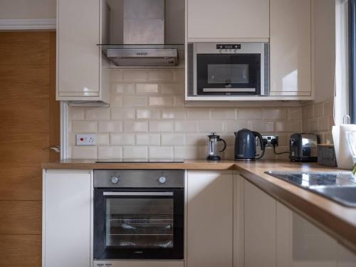 a kitchen with a stove and a microwave at Lodge W Hot Tub, Outdoor Dining In National Park in Otterburn