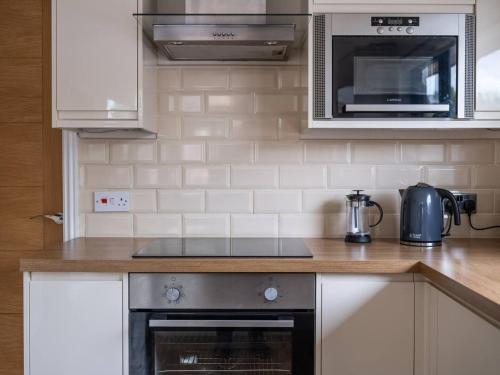 a kitchen with a stove and a microwave at Lodge W Hot Tub, Outdoor Dining In National Park in Otterburn