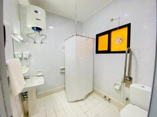 a white bathroom with a sink and a toilet at Zee Hotel in Dubai