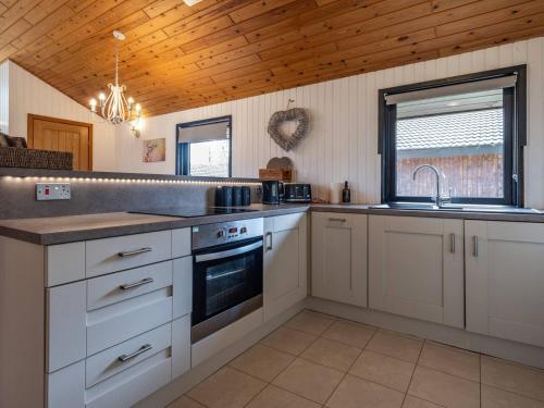 a kitchen with white cabinets and a sink at Cabin W Hot Tub, Sauna, King Beds, National Park in Otterburn